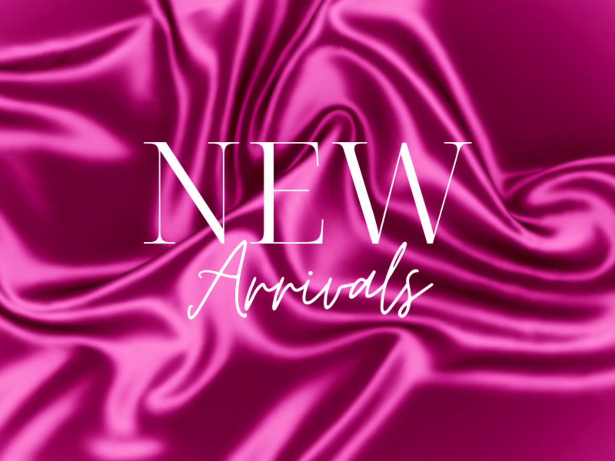A magenta satin fabric background with draped folds and the centered text 'NEW Arrivals' in white serif and script lettering.